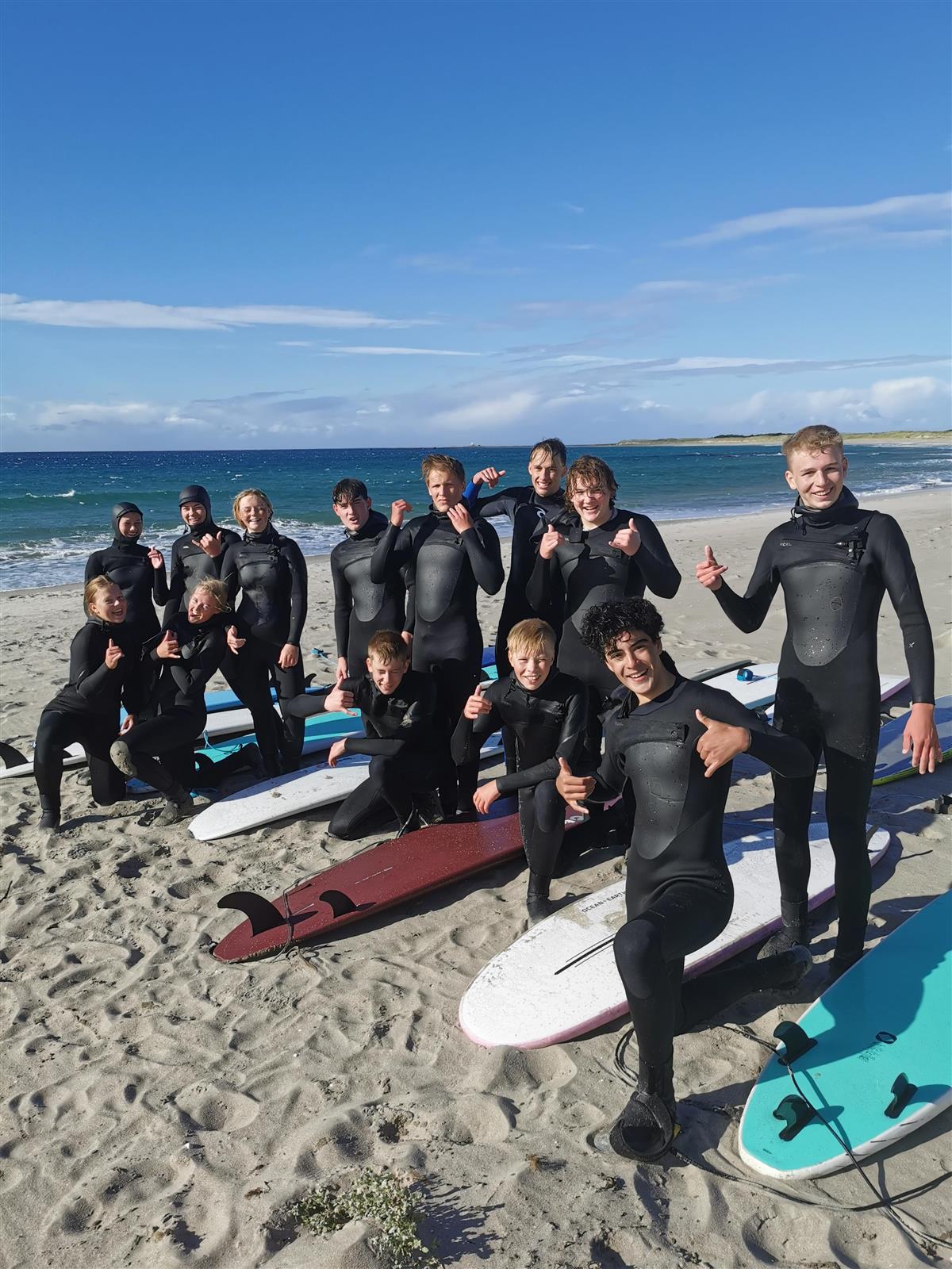 Elever på strand med surfebrett - Klikk for stort bilde